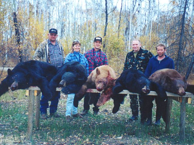 One more look at a table full of black bears. Head guide and outfitter/guide dressed in blue and red plaid jackets proudly display our hunters\' catch. For a first day, not too shabby!