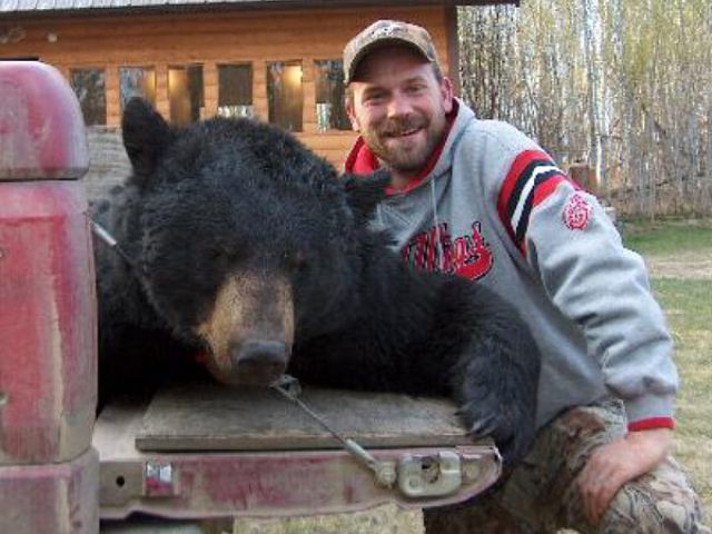 Archery hunter, Cory, in a close up with his monster bear. Many serious photos were taken too. A sharp eye and an accurate shot and this bear didn\'t take more than a few steps once he had been arrowed. The camp of 5 clients all tagged their trophy bear giving us another 100% on a non-baited hunt.