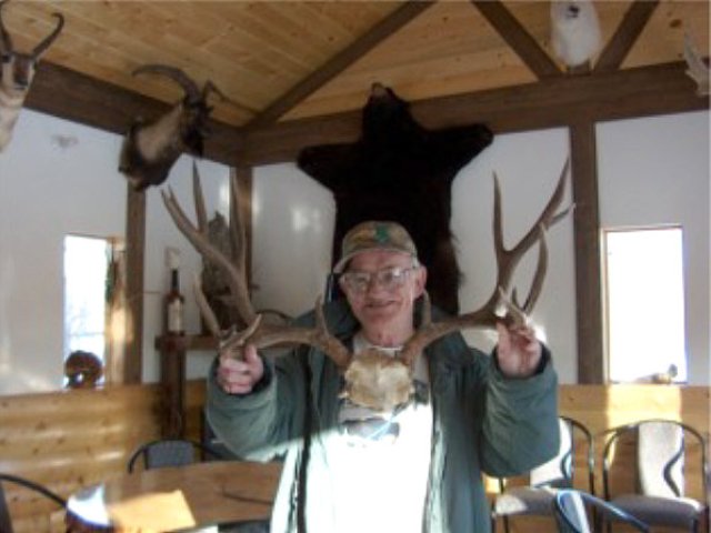 A spread of 30 inches but only a score of 166 shows that spread isn\'t everything. Not always do the widest racks make the best trophies however, Reg, is all smiles as he holds this trophy in the camp kitchen. An early season hunt produced this buck in just a few hours.