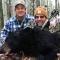 Outfitter and hunter joking as they squat behind Brent\'s bear for a photo. This bear was taken on a baited hunt off an active bait barrel loaded with our own secret recipe of bear foods. This trophy is one of two bears my hunter shot at with his bow. An excellent shot and a great hunter to have in camp.