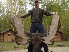 A record book moose and another happy hunter. Clayton proudly shows off his trophy on the skinning table. Way up in the books this monster bull was held by my yearning cow call giving another client a successful memory. Many more of these trophy bulls roam our hunting areas.
